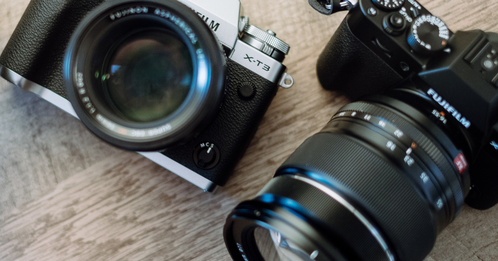 Duas câmeras fotográficas profissionais dispostas lado a lado em cima de uma superfície