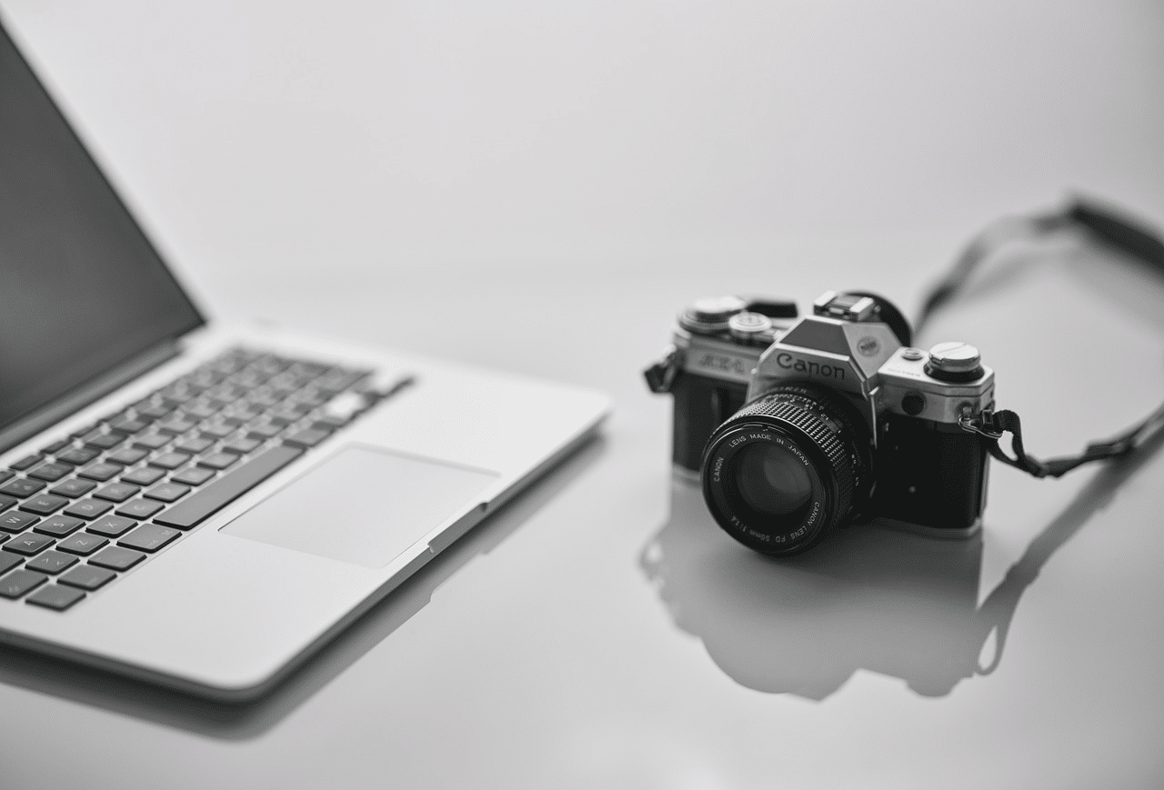 notebook sobre uma mesa branca com uma câmera ao lado